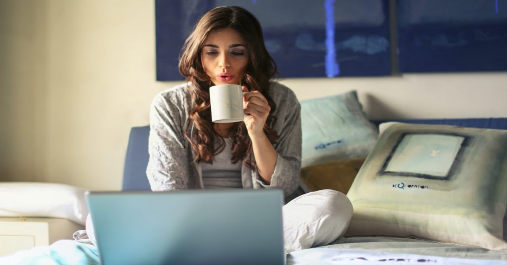 Girl drinking coffee working on laptop